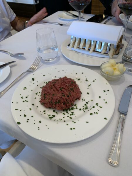 Prato de steak tartare de carne bovina temperada e salpicada com ervas em uma mesa de restaurante com toalha branca no Zinfandel's em Zagreb, Croácia.