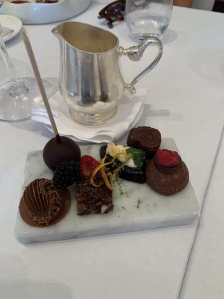 Seleção de sobremesas finas de chocolate e frutas vermelhas servida em uma placa de mármore branco ao lado de uma leiteira de prata no restaurante Zinfandel's em Zagreb, Croácia.