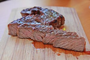 Corte de carne bovina grelhada e fatiada ao ponto na tábua de madeira do restaurante Fuego Celeste.